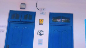 Una porta blu con un cartello che riporta la scritta 'Benvenuti' e 'Si prega di togliersi le scarpe'.
