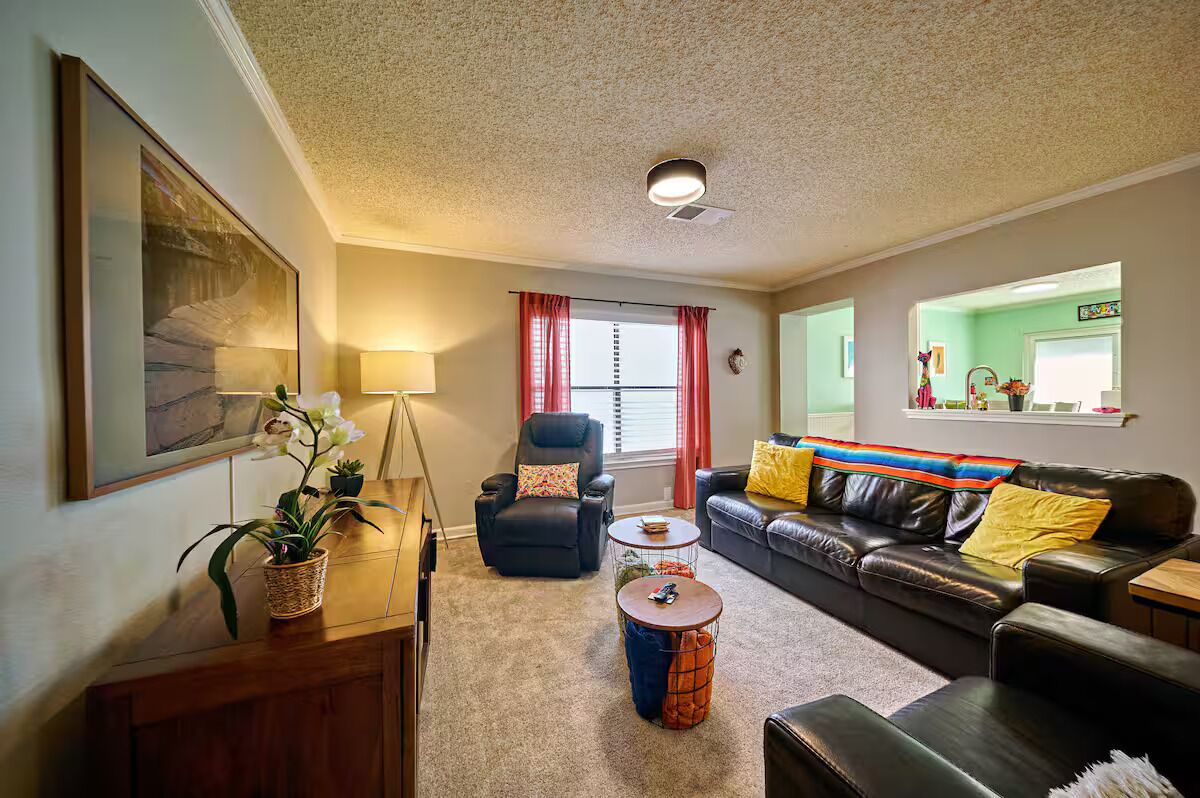 A living room with a sofa, armchair, coffee table, and a potted plant.
