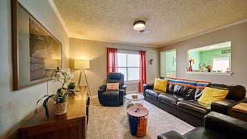A living room with a sofa, armchair, coffee table, and a potted plant.