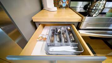 A kitchen drawer with utensils and a cookbook.