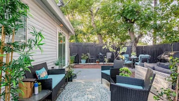 An outdoor patio with wicker furniture, a patterned rug, and potted plants.