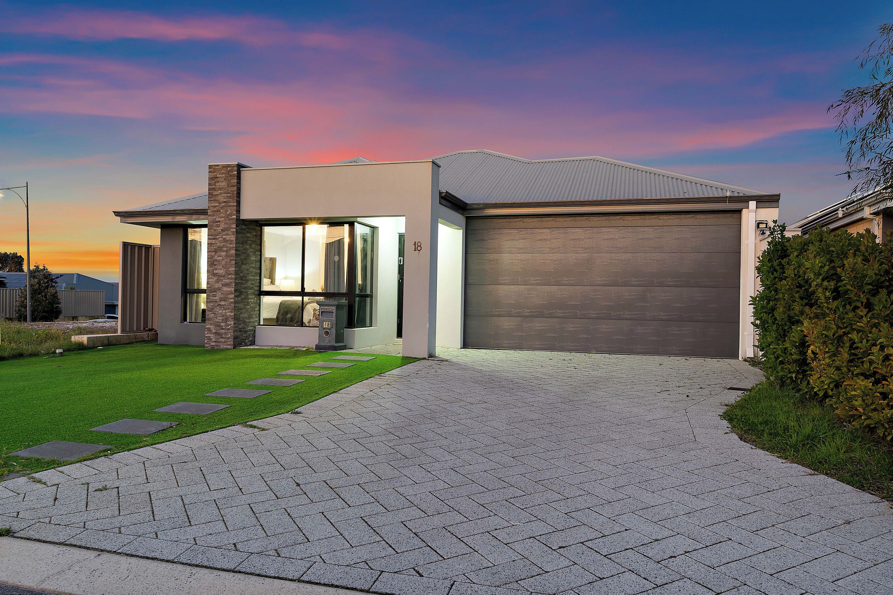 A modern two-story house with a garage, a well-maintained lawn, and a paved driveway.