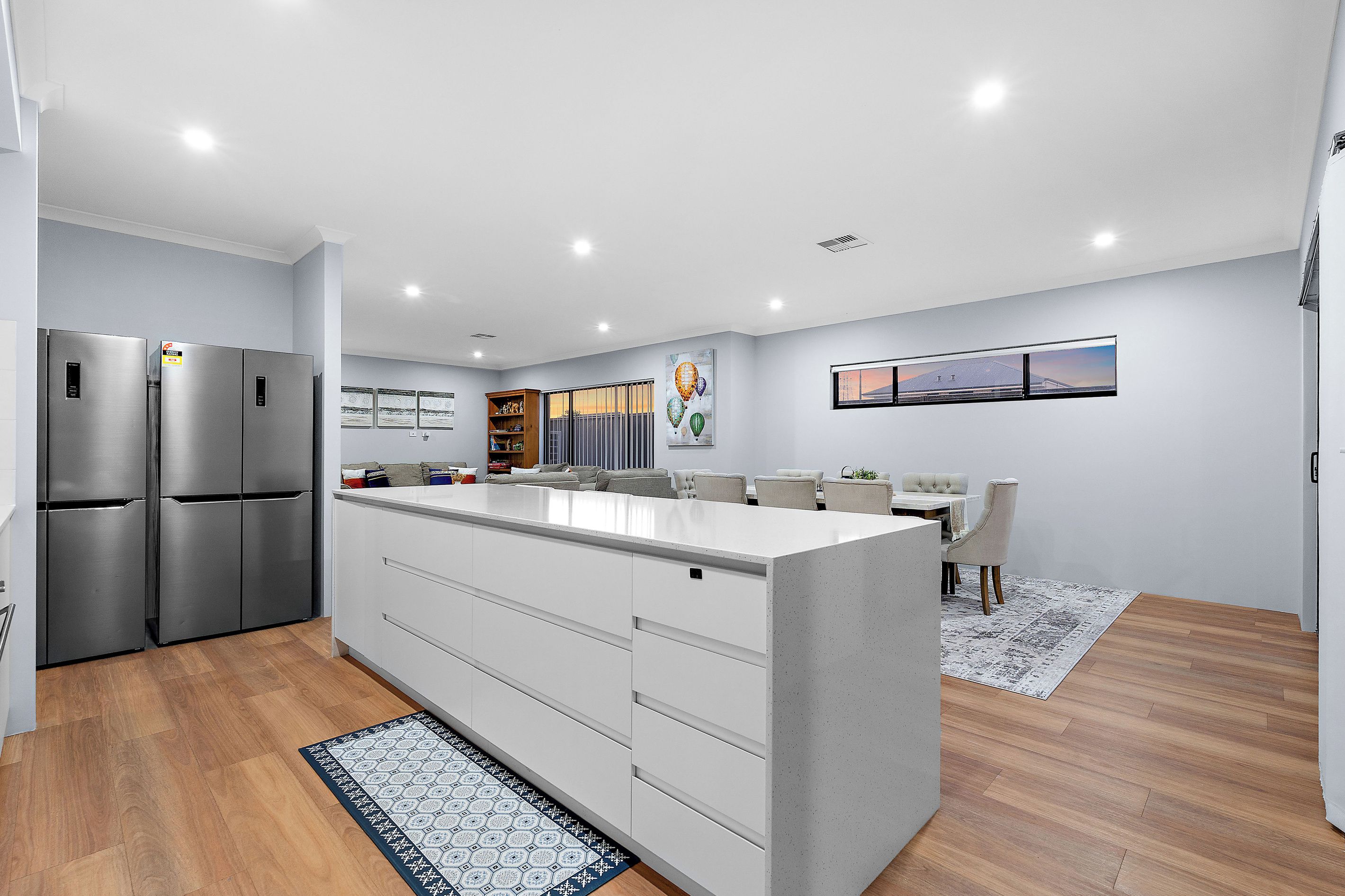 A modern kitchen with a central island, stainless steel appliances, and a dining area with a view.