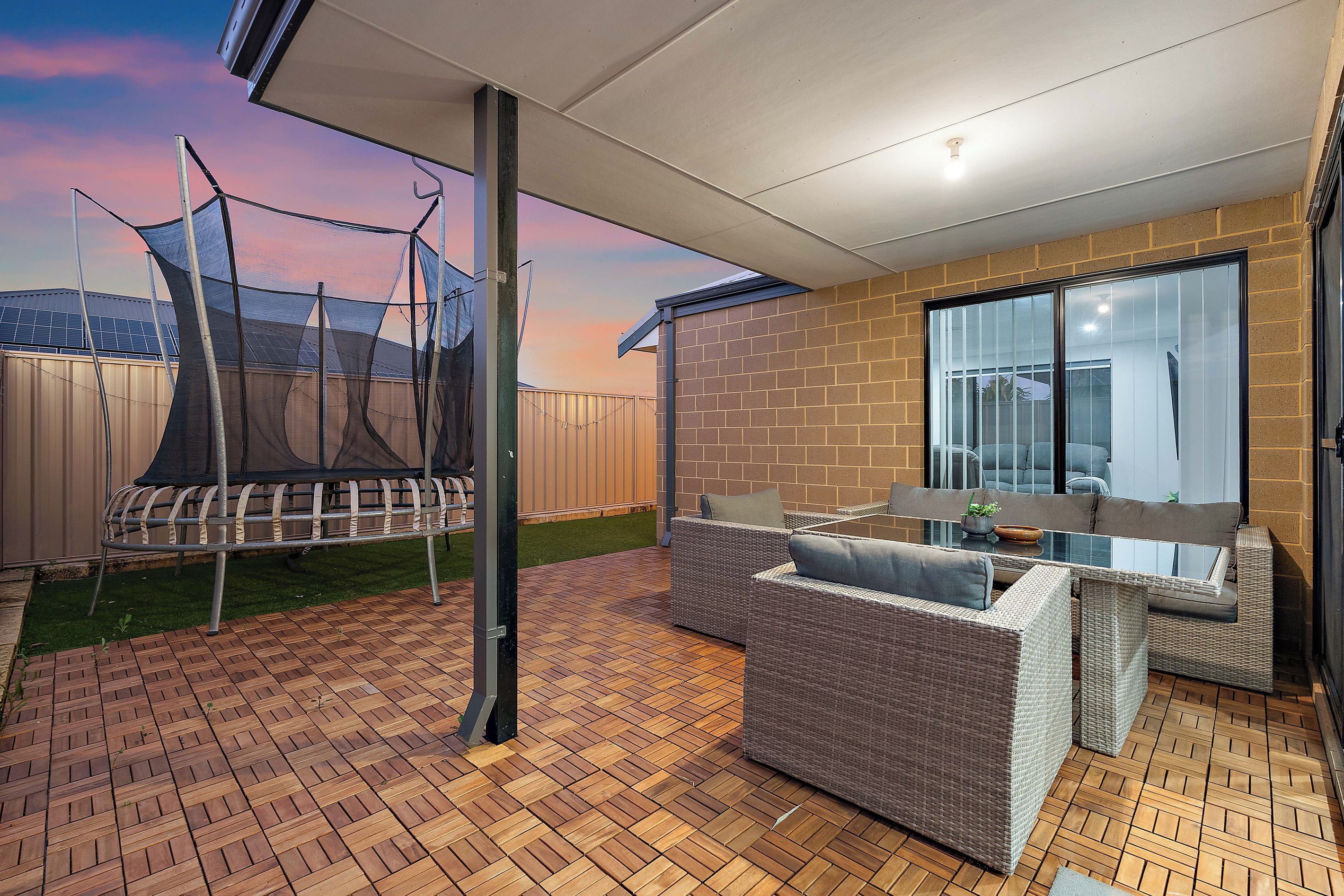 A patio area with a table and chairs, a swing set, and a brick wall.
