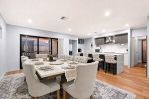 A modern kitchen with a central island, a dining area with a table set for six, and a large window with a view.
