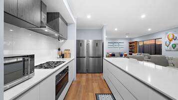 A modern kitchen with stainless steel appliances, white cabinetry, and a wooden floor.