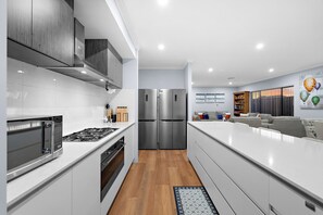A modern kitchen with stainless steel appliances, white cabinetry, and a wooden floor.