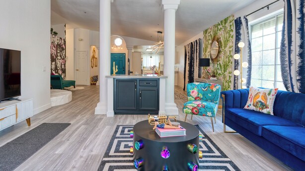 Een moderne woonkamer met een blauwe bank, een ronde salontafel en een televisie op een witte kast.
