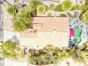 Eine Luftaufnahme einer Anlage mit einer großen, offenen Terrassenfläche, einem Schwimmbecken und umgebender Bepflanzung.