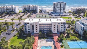 A hotel with multiple floors, a swimming pool, and a tennis court. - Ocean Walk Condo: Classy Beachy Retreat in charming New Smyrna Beach (New Smyrna Beach)