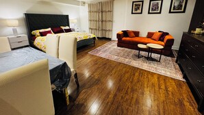 Una habitación de hotel moderna con una cama, un sofá, una mesita y un escritorio.