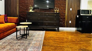 Una sala de estar moderna con un panel de pared de madera oscura, un mueble de entretenimiento negro y un televisor de pantalla plana.