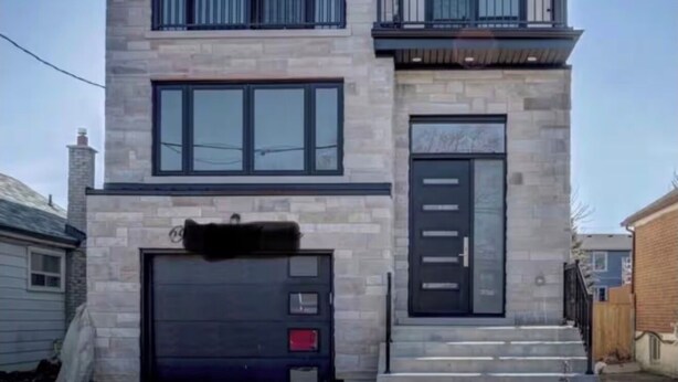 Una casa de dos pisos con garaje, un balcón en el nivel superior y una puerta principal.
