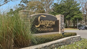 A sign for Sawgrass Players Club with a stone pillar and a landscaped area with grass and flowers. - Tee to Sea Retreat - Inside TPC Sawgrass Gated Community, Ponte Vedra Beach  (Palm Valley)