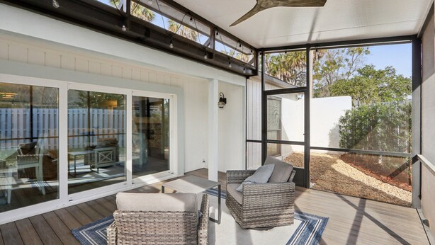 A covered outdoor area with wicker furniture, a ceiling fan, and large glass doors leading to a backyard. - Tee to Sea Retreat - Inside TPC Sawgrass Gated Community, Ponte Vedra Beach  (Palm Valley)