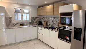 Una cocina moderna con armarios blancos, un salpicadero de mármol y electrodomésticos de acero inoxidable.
