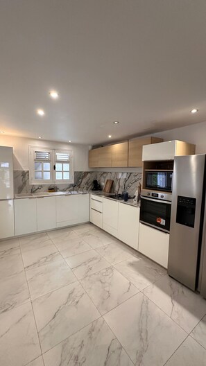 A modern kitchen with white cabinets, a marble backsplash, and stainless steel appliances. - Magnificent villa with large pool and pleasant living space. (Rivière-Salée)
