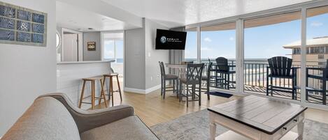 Un interior moderno con comedor, sofá, televisor y balcón con vistas.