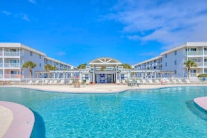 Een resort met een centraal gelegen zwembad, meerdere balkons en een overdekte entree.