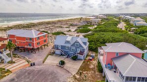 Een kustgebied met woonhuizen nabij het strand, met een opvallend blauw huis met balkon en een rood huis met veranda.