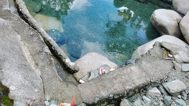 A stone pool with clear water, surrounded by rocks and steps leading to a house with a red roof. - Australian Hotel Hungduan (Hungduan)