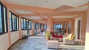 A spacious hotel lobby with large windows, a geometric patterned floor, and a central seating area with a sofa and armchairs. - Australian Hotel Hungduan (Hungduan)