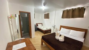 A bedroom with a wooden bed, a small table, a mirror, a window with curtains, and a door leading to a bathroom. - Australian Hotel Hungduan (Hungduan)