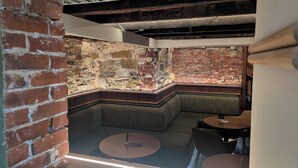 Un área de descanso con sofás, pared de ladrillo y una pequeña mesa redonda.