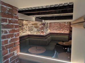 Un área de descanso con sofás, pared de ladrillo y una pequeña mesa redonda.