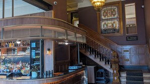 Zona de bar con barra, escalera y candelabro.