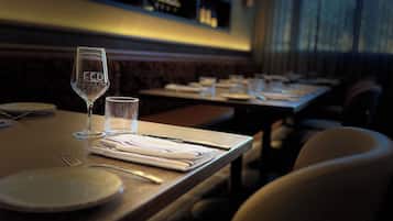 A restaurant interior with tables set for dining, clear glassware, and a modern design.