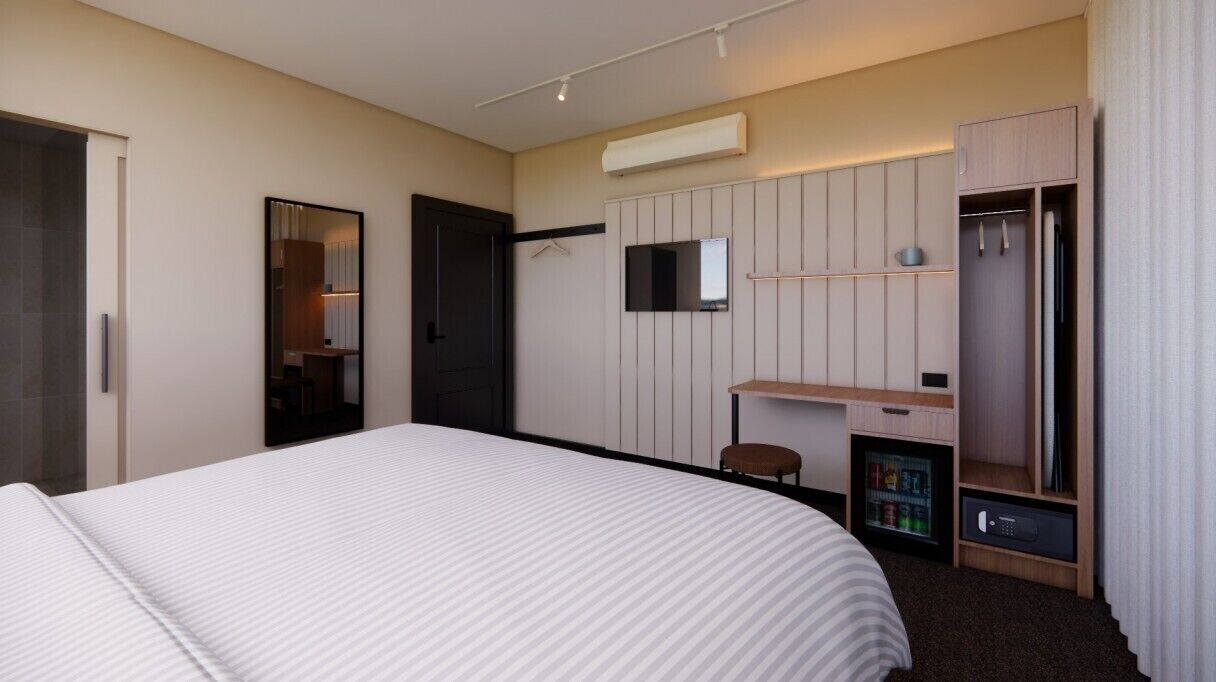 Habitación de hotel con cama, escritorio, silla, armario, espejo y minibar.
