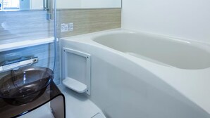 Un baño moderno con cabina de ducha de vidrio, bañera e lavamanos de vidrio.