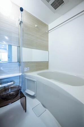 Een moderne badkamer met een douchecabine van glas, een badkuip en een wastafel van glas.