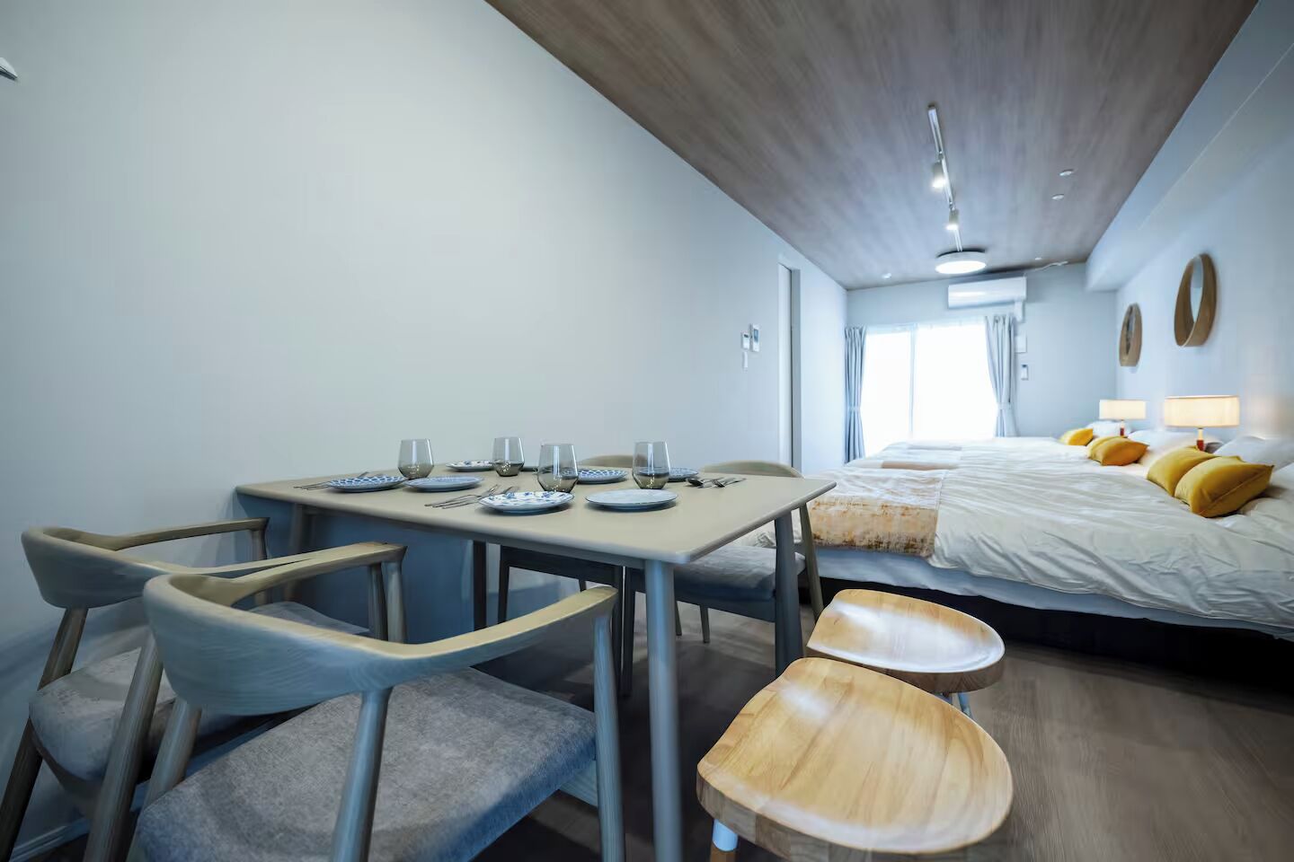 Une pièce compacte comprenant une table à manger pour quatre personnes, un lit avec des coussins jaunes et un petit coin salon.