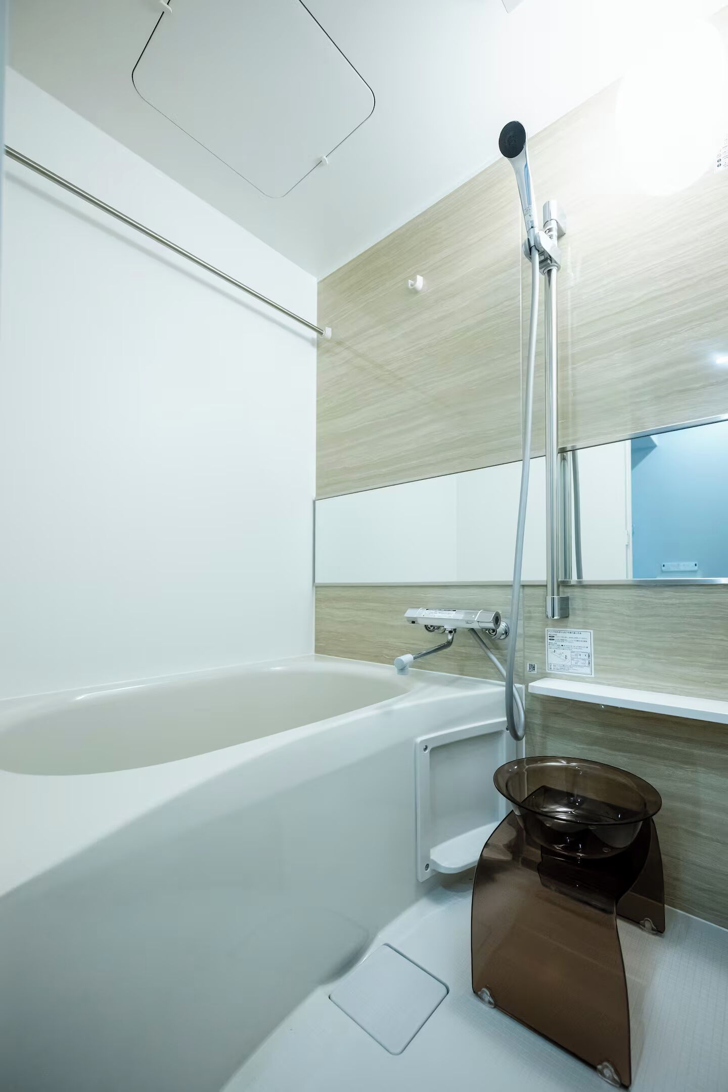 A modern bathroom with a bathtub, a shower head, and a mirror.