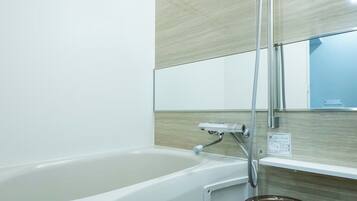 A modern bathroom with a bathtub, a shower head, and a mirror.