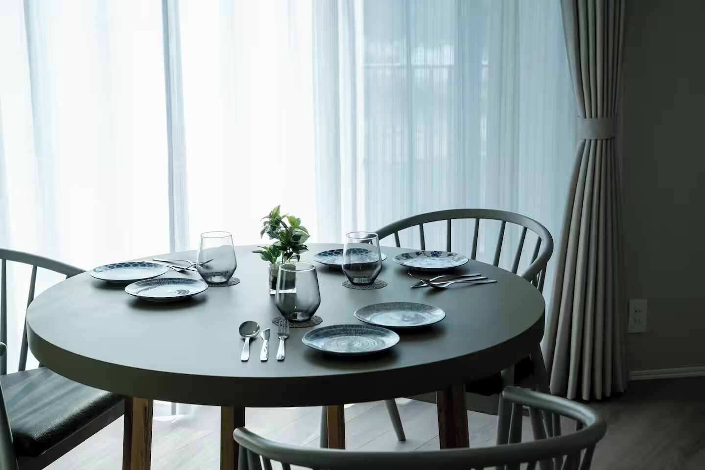 A round dining table with plates, glasses, and cutlery set for four.