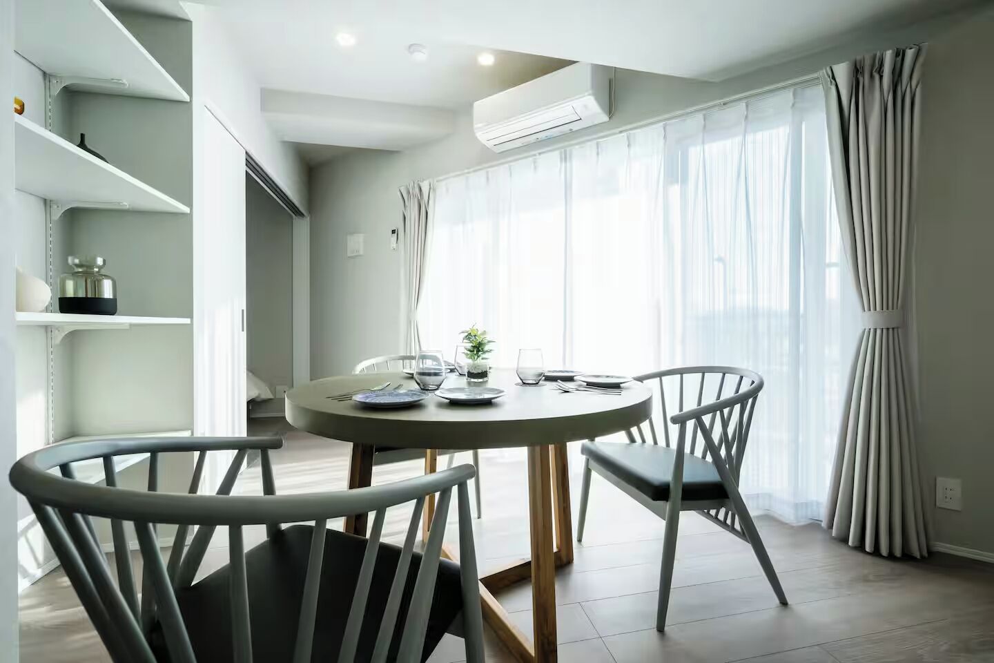 A dining area with a round table, two chairs, and a potted plant.