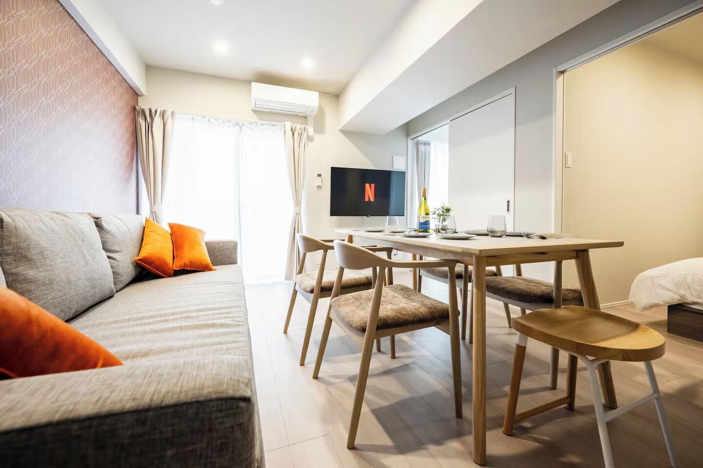 Una sala de estar moderna con un sofá, una mesa de comedor con sillas, un televisor de pantalla plana y una minibar.