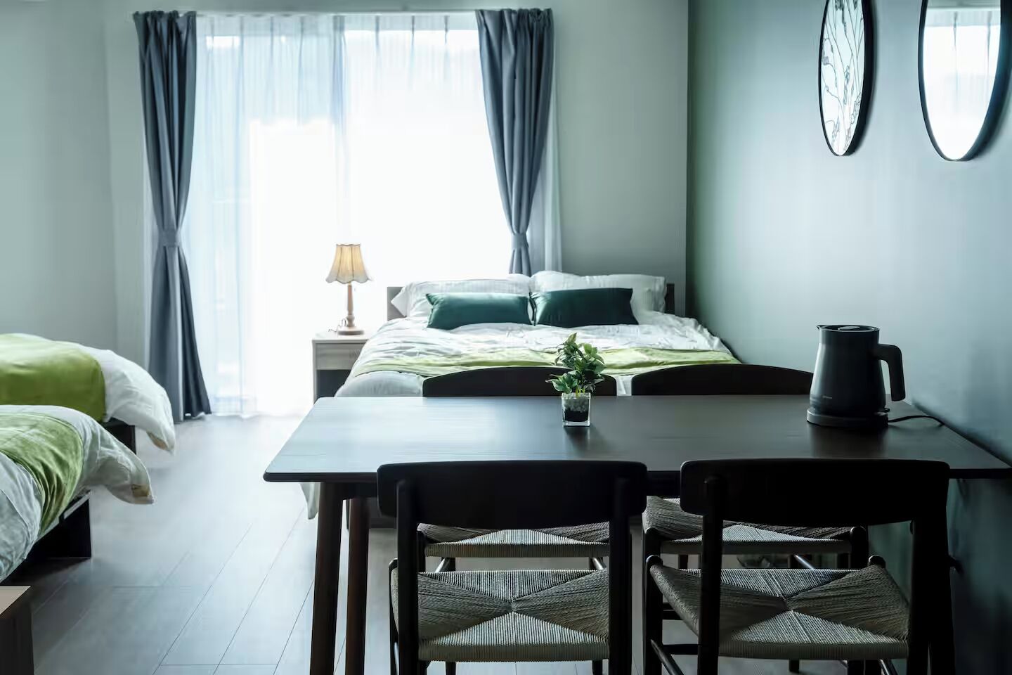 Una habitació d'hotel moderna amb un llit, una taula de menjador amb cadires, una petita planta i un brollador d'aigua.