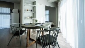Un espace repas moderne avec une table ronde, quatre chaises et une étagère intégrée où sont exposés des objets décoratifs.