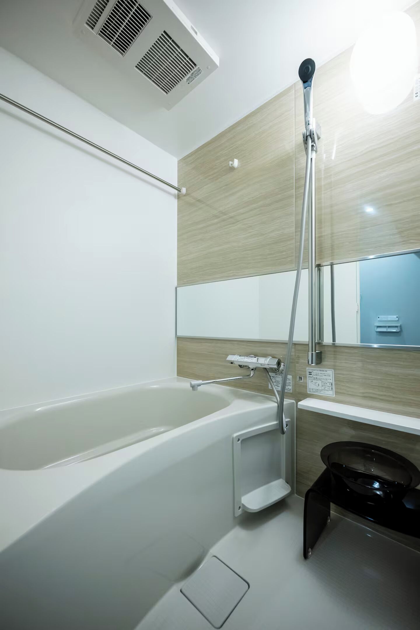 A modern bathroom with a bathtub, a showerhead, and a mirror.