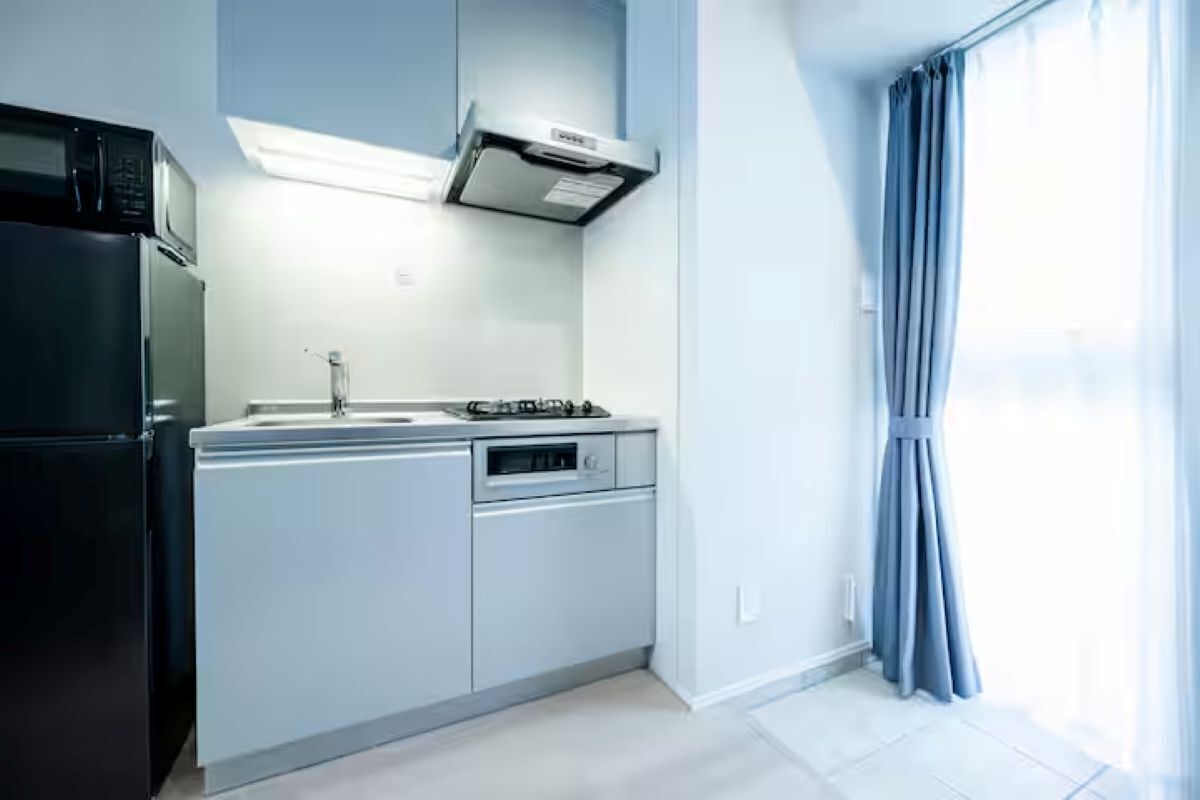 Une cuisine moderne avec un réfrigérateur noir, un four encastré et une cuisinière à gaz.