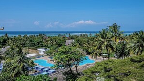 A resort with a swimming pool, palm trees, and a view of the ocean. - Diani Beachfront Paradise (Diani Beach)