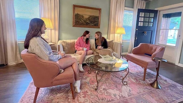 Ein Wohnzimmer mit einer Couch, Sesseln, einem Couchtisch und einem gemusterten Teppich.