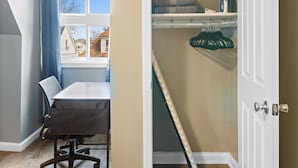 Een kamer met een eettafel, een stoel, een schoenenrek en een deur naar een inloopkast.