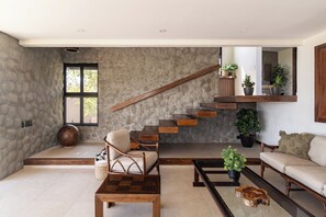 A spacious living area with a high ceiling, a wooden staircase, and a large window providing natural light. - Ocean Breezes & Mountain Views — Your Cliffside Escape in La Libertad (El Sunzal)