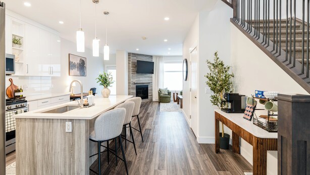 A modern kitchen with a central island, wooden flooring, and pendant lighting. - Luxury 3BR Retreat Near Downtown | 5-PC King Ensuite +Private Balcony | Sleeps 6 (Calgary)