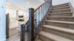 A modern kitchen with white cabinets, a stainless steel refrigerator, and a microwave. - Luxury 3BR Retreat Near Downtown | 5-PC King Ensuite +Private Balcony | Sleeps 6 (Calgary)